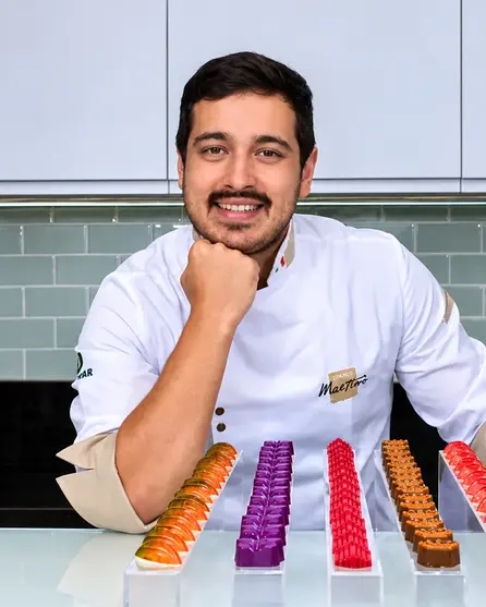 Gustavo Ono, de dólmã branca, com fileiras de bombons coloridos