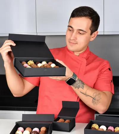 Gustavo Ono segurando uma caixinha de trufas aberta